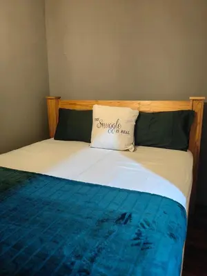a bed with a pillow on top of it at The Cozy Cabin in Pretoria