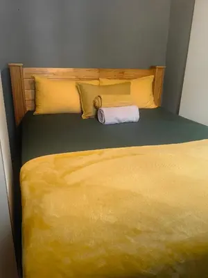 a bed with a yellow blanket and a towel on it at The Cozy Cabin in Pretoria