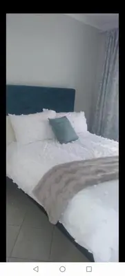 a bed with white sheets and a blue pillow at Lerato's Guesthouse in Polokwane
