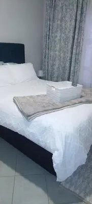 a bed with white sheets and two boxes on it at Lerato's Guesthouse in Polokwane