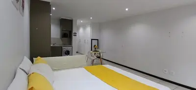 a large white room with a large bed and a kitchen at Secured Studio Apartment in Sandton