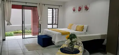 a bedroom with a bed and a table with a vase at Secured Studio Apartment in Sandton