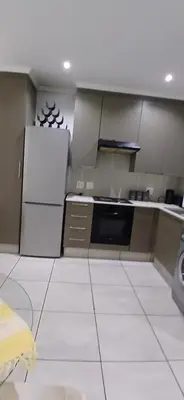 a kitchen with a refrigerator and a white tile floor at Secured Studio Apartment in Sandton