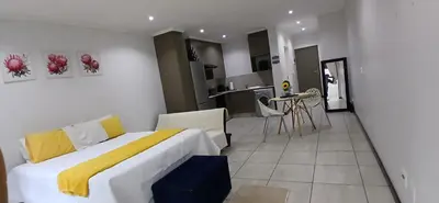 a bedroom with a large bed and a kitchen at Secured Studio Apartment in Sandton