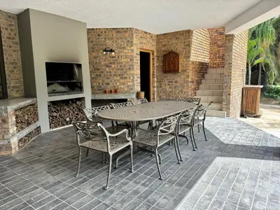 a patio with a table and chairs and a fireplace at Ukujabula in Groblersdal