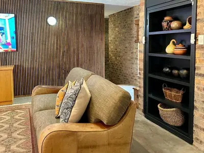 a living room with a couch and a shelf with vases at Ukujabula in Groblersdal
