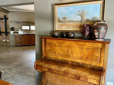 a wooden piano with vases and a painting on the wall at Ukujabula in Groblersdal