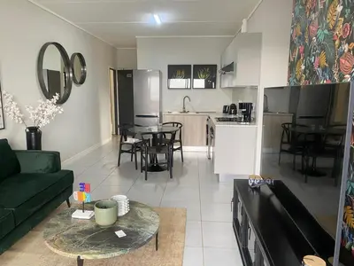 a living room with a green couch and a kitchen at Big deana home in Pretoria