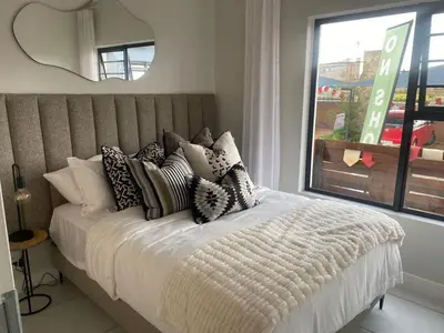 a bed with many pillows on it with a window at Big deana home in Pretoria