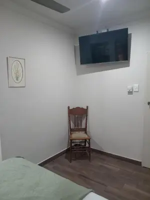 a room with a chair and a tv on a wall at Green Haven in Benoni