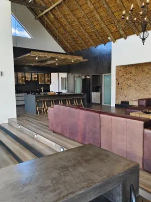 a large room with a bar with benches and tables at Sitrah Private Lodge, Mabalingwe in Mabula