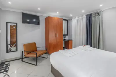 a hotel room with a bed and a chair at Moyres Guest House in Witbank
