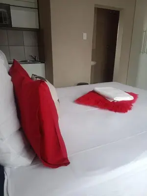 a bed with red and white pillows on it at Rasesa Guesthouse in Soshanguve