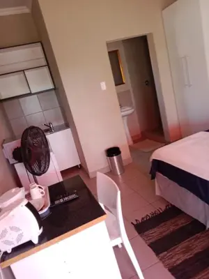 a room with a bed and a desk with a phone at Rasesa Guesthouse in Soshanguve