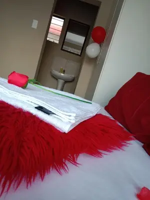 a bedroom with a red and white blanket on a bed at Rasesa Guesthouse in Soshanguve