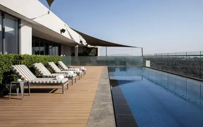 a pool on the roof of a building with lounge chairs at Menlyn Maine Trilogy Collection in Pretoria
