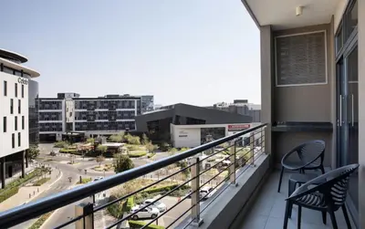 a balcony with two chairs and a view of a city at Menlyn Maine Trilogy Collection in Pretoria
