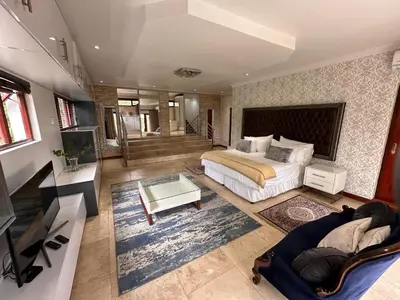 a large bedroom with a bed and a living room at Concordia Boutique Venue in Midrand