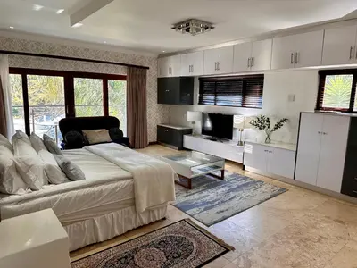 a living room with a large bed and a kitchen at Concordia Boutique Venue in Midrand