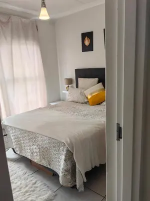 a white bedroom with a bed with a yellow pillow at Blyde in Pretoria