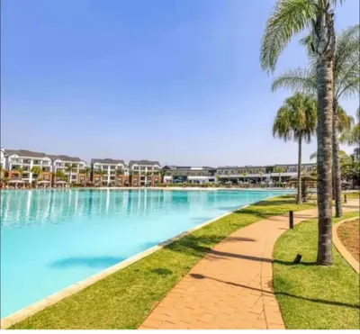 a large swimming pool with palm trees and condos at Blyde in Pretoria