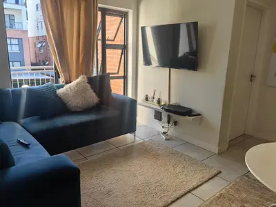 a living room with a blue couch and a tv at Blyde in Pretoria