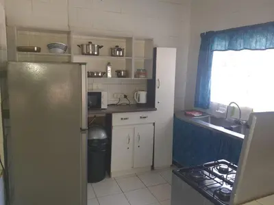 a small kitchen with a refrigerator and a sink at Cottage 2 at Cynthias Country in Hartbeespoort