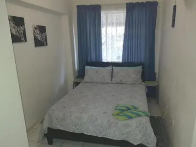 a bedroom with a bed with two pillows and a window at Cottage 2 at Cynthias Country in Hartbeespoort