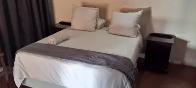 a bedroom with a bed with white sheets and pillows at Snowy Owl in Burgersfort