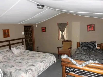 a bedroom with two beds and a chair at Inniberg Nylstroom in Nylstroom