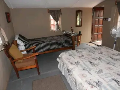 a bedroom with a bed and a chair and a window at Inniberg Nylstroom in Nylstroom