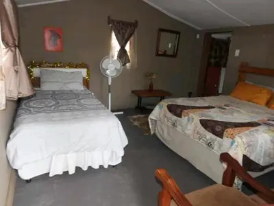 a bedroom with two beds and a table with a fan at Inniberg Nylstroom in Nylstroom