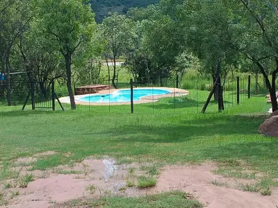 a swimming pool in a park with a fence at Inniberg Nylstroom in Nylstroom