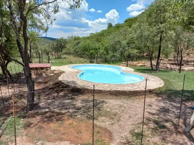 an empty swimming pool in a yard with trees at Inniberg Nylstroom in Nylstroom