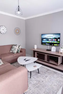 a living room with a couch and a table and a tv at Viata Luxe Guesthouse in Phalaborwa