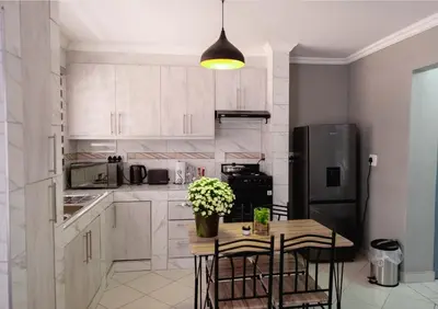 a kitchen with a table with chairs and a refrigerator at Viata Luxe Guesthouse in Phalaborwa