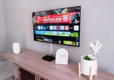 a flat screen tv on a wall above a table at Viata Luxe Guesthouse in Phalaborwa
