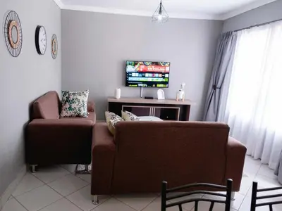 a living room with a couch and a chair at Viata Luxe Guesthouse in Phalaborwa