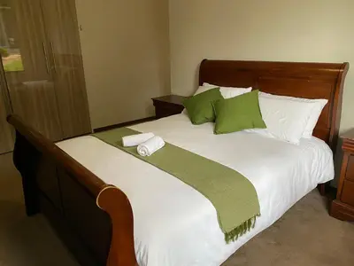 a bed with green and white sheets and pillows at Bridgelamour Guest house1 in Hartbeespoort