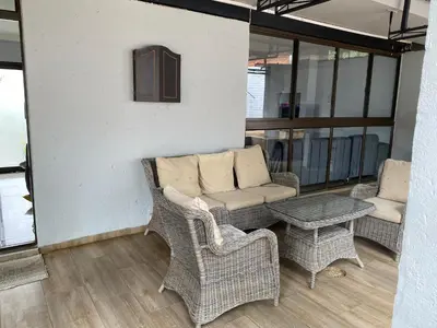 a patio with wicker chairs and a couch and a table at Bridgelamour Guest house1 in Hartbeespoort