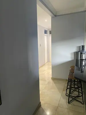 a room with a white wall and a table and stool at Bridgelamour Guest house1 in Hartbeespoort