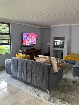 a living room with a couch and a flat screen tv at Bridgelamour Guest house1 in Hartbeespoort