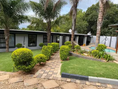 a garden with bushes and trees and a house at Bridgelamour Guest house1 in Hartbeespoort