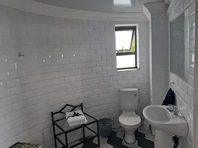 a white bathroom with a toilet and a sink at THE GALLARY INN, Kosmos, Hartbeespoort in Hartbeespoort