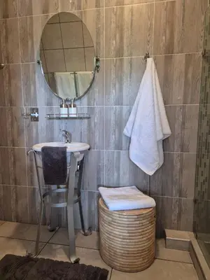 a bathroom with a sink and a mirror and a stool at Highveld Guesthouse in Centurion