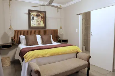 a bedroom with a large bed and a chair at Highveld Guesthouse in Centurion