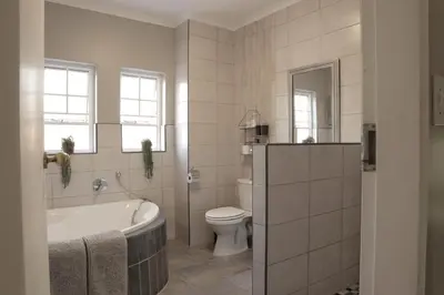 a bathroom with a bath tub and a toilet at Highveld Guesthouse in Centurion