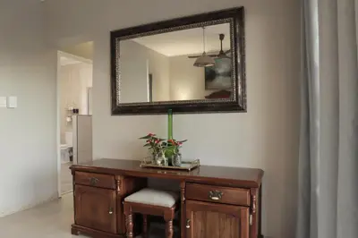 a mirror on a wall above a wooden desk with a plant on it at Highveld Guesthouse in Centurion