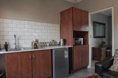 a kitchen with wooden cabinets and a stainless steel refrigerator at Highveld Guesthouse in Centurion