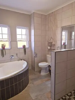 a bathroom with a bath tub and a toilet at Highveld Guesthouse in Centurion